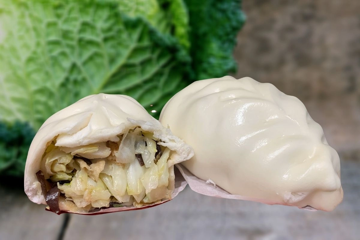 孔子饅頭【子木高麗菜包】切面特寫，內餡可見高山高麗菜、有機胡蘿蔔、香菇、黑木耳絲及豆皮，內餡豐富清甜。