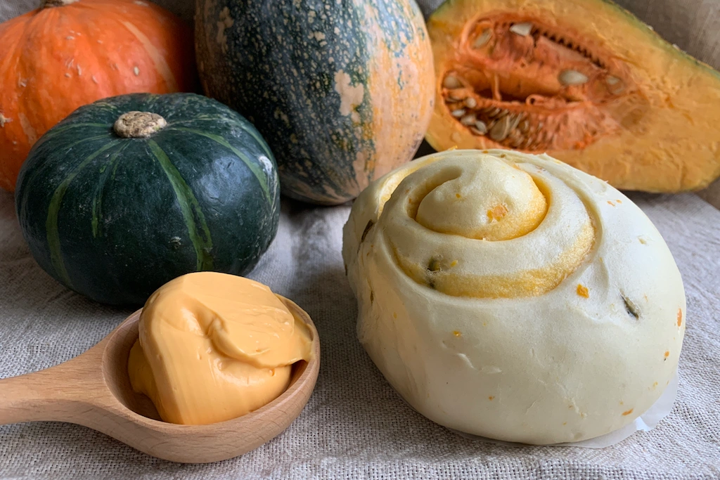 孔子饅頭【南子-南瓜乳酪饅頭】特寫，饅頭呈天然澄黃色，可見香濃優質乳酪餡，奶素可食。